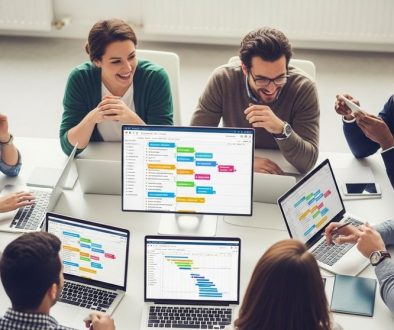 Ein Agenturteam arbeitet gemeinsam an einem Tisch mit Projektmanagement Software auf Laptops.