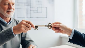 Ein erfahrener Unternehmer übergibt seinem Nachfolger symbolisch einen Schlüssel während eines Management Buy Outs.