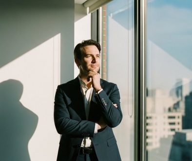 Nachdenklicher Agentur-Inhaber blickt aus dem Bürofenster, symbolisch für passives Einkommen.
